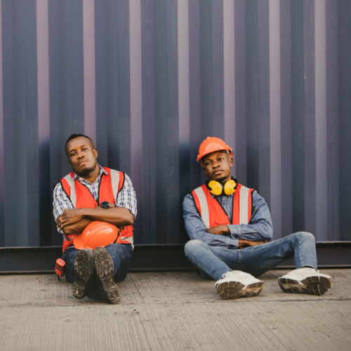 Two migrant workers pose for a picture in their construction gear for the Human Rights Foundations report titled "Authoritarianism and Trafficking in Persons".