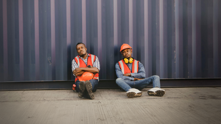 Two migrant workers pose for a picture in their construction gear for the Human Rights Foundations report titled "Authoritarianism and Trafficking in Persons".