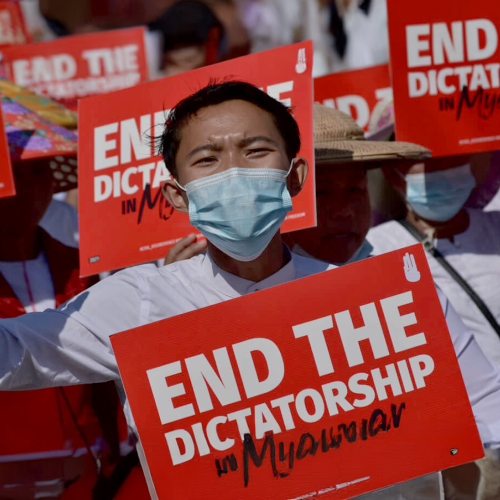 Burmese activists holding up sites reading "End the dictatorship"