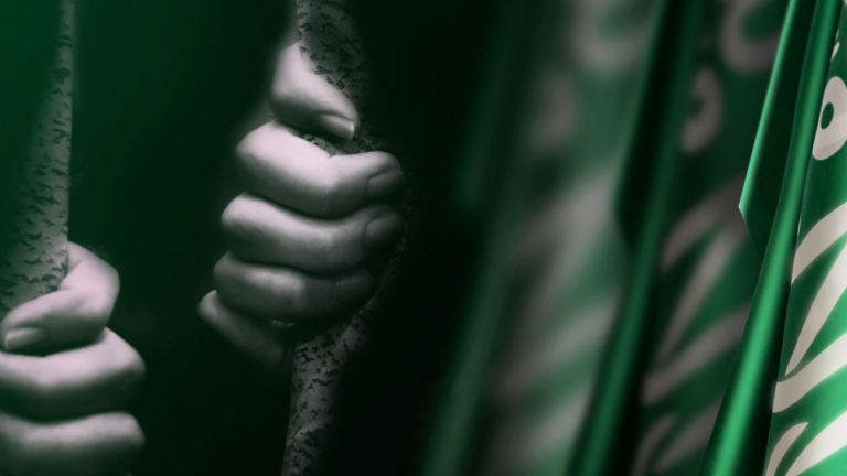 Hand gripping a silk scarf with green undertones representing trafficking in Saudi Arabia