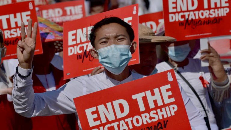 Burmese activists holding up sites reading "End the dictatorship"