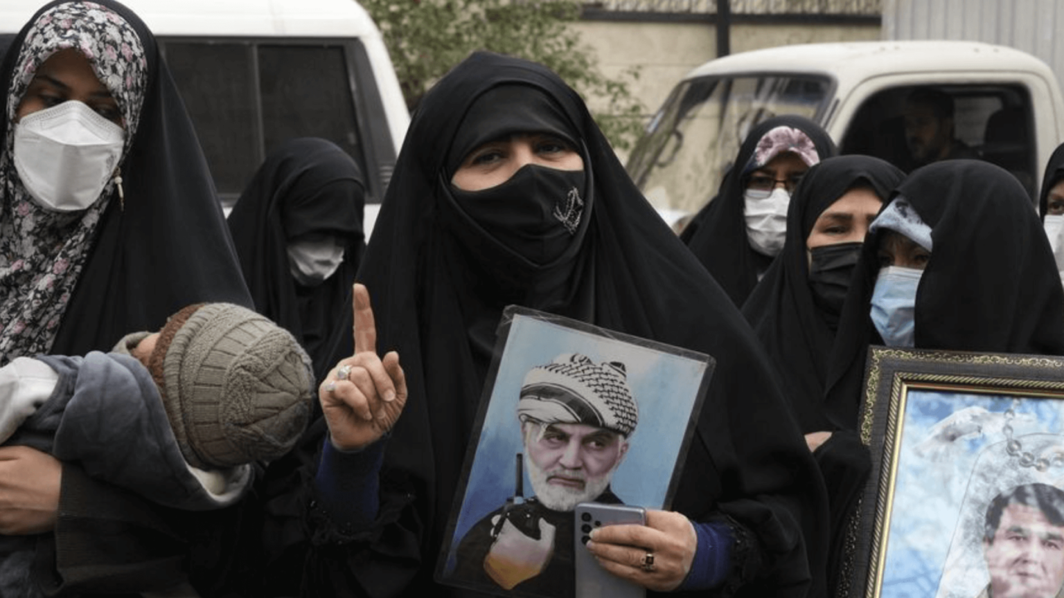 Iranian women holding photographs of Iranian leaders