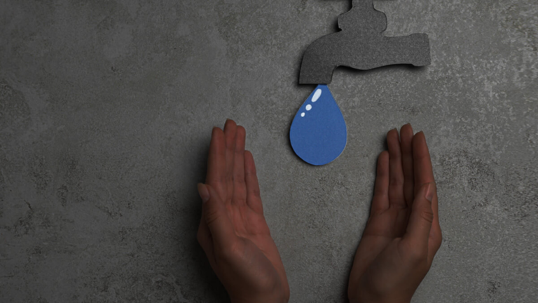 Fake water dropping into cupped hands representing water scarcity