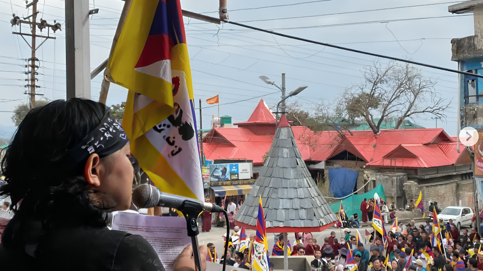 Youthquake Report - Students for a Free Tibet India Director Tenzin Passang speaks before a crowd waving the Tibetan flag on the 65th anniversary of the Tibetan National Uprising 1959 in Dharamsala, India