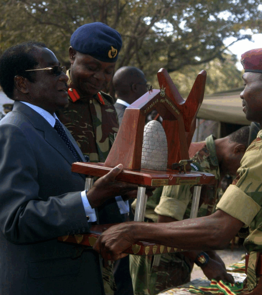 Zimbabwean ruler Robert Mugabe presents an award to a soldier at a military shooting competition in Harare